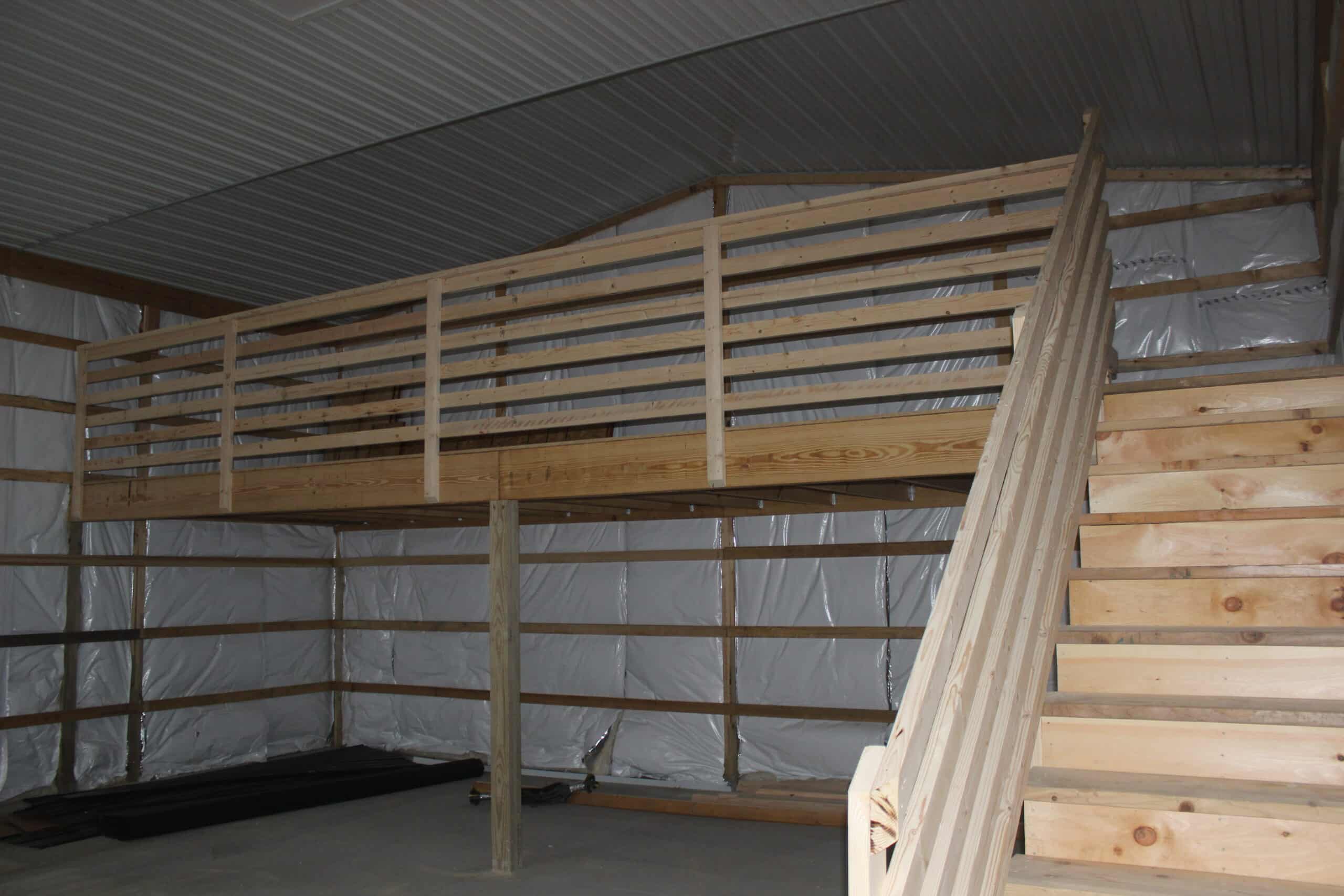 The interior of a metal garage with exposed metal siding, wooden framing, and custom-built wooden shelving along the walls. The ceiling features wooden trusses.