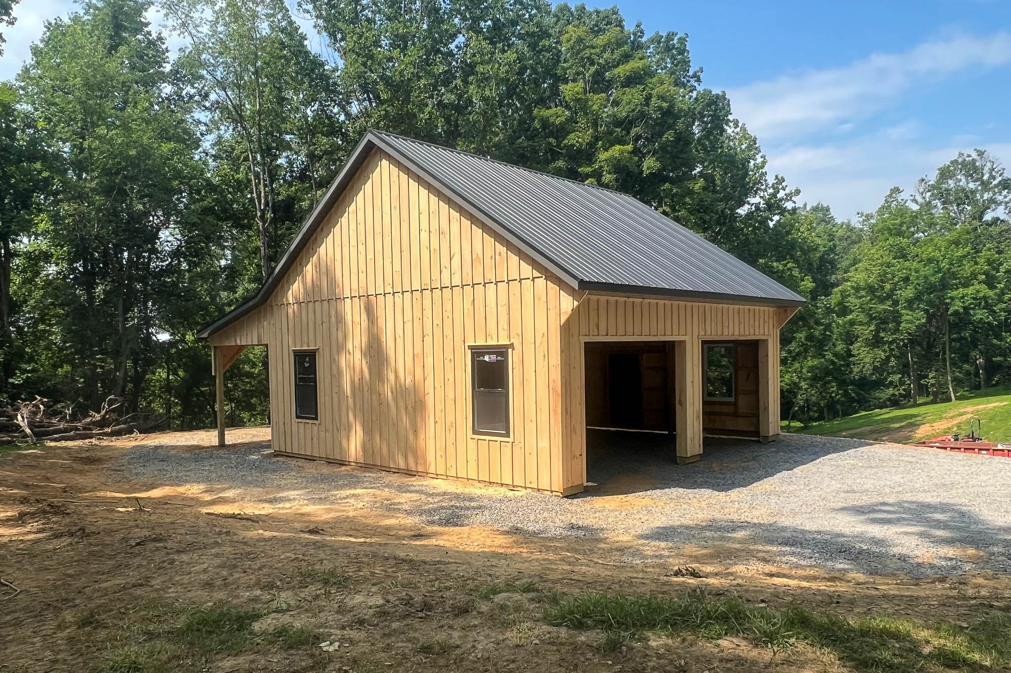 Wooden garage under construction with a poured concrete driveway and open garage bays framed in natural timber.
