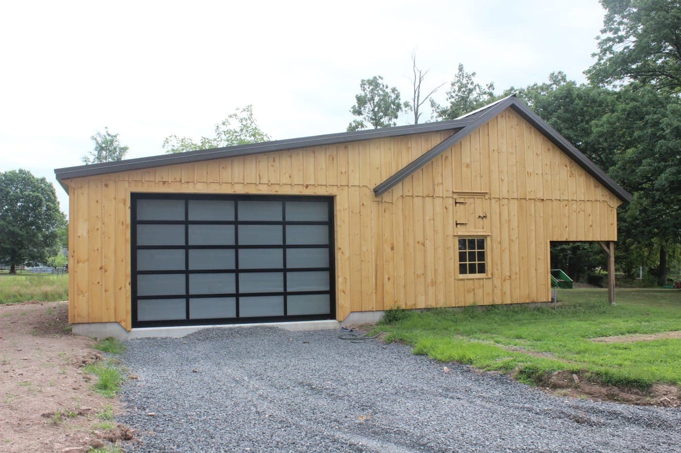 full-view aluminum garage door with translucent panels installed on a wood-sided post-frame building.
