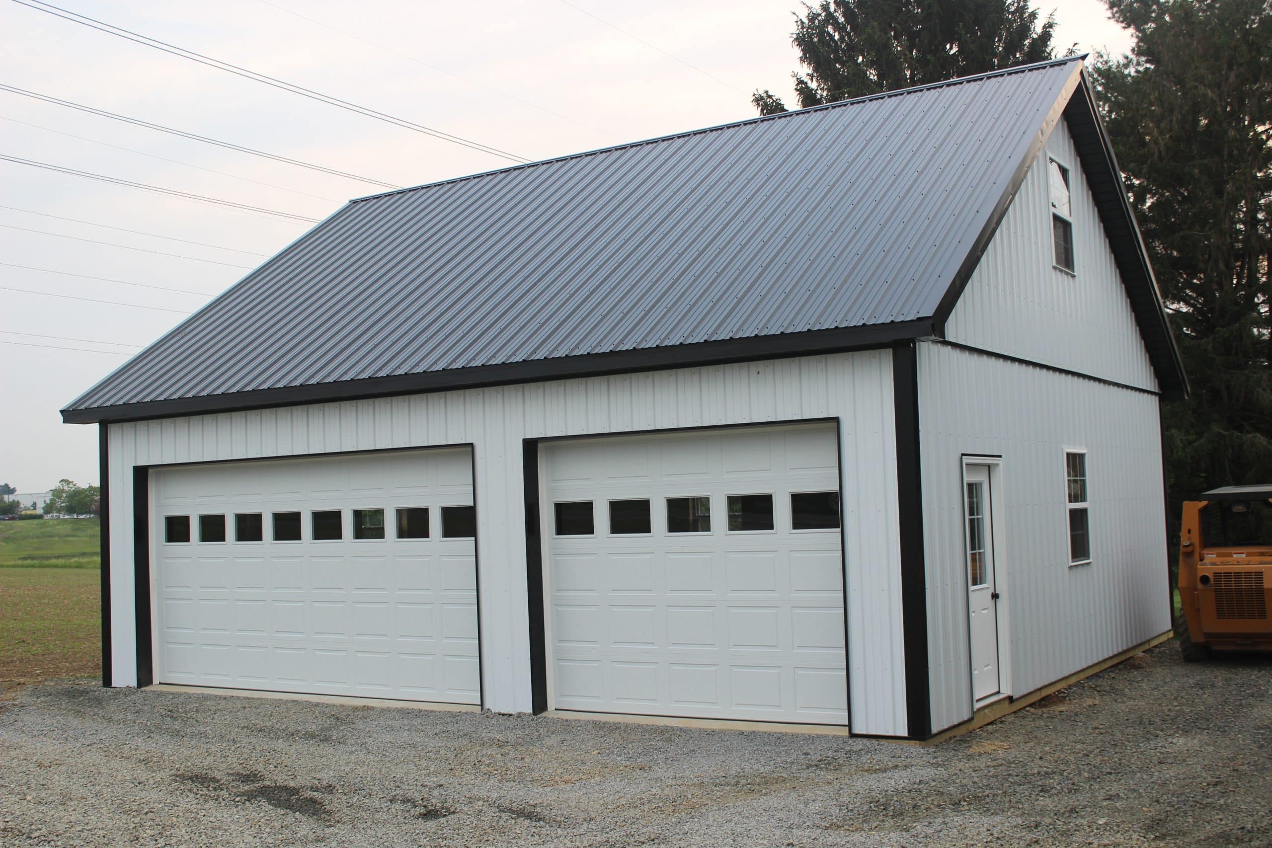 white overhead garage doors with window inserts installed on a post-frame garage building.